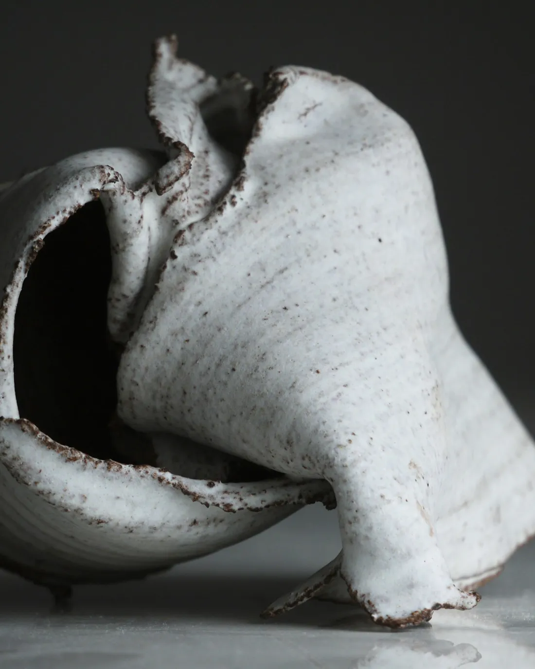 A white stoneware piece with a hand-folded rim, close up